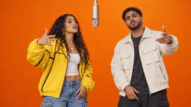 A couple in matching streetwear rapping in an orange booth